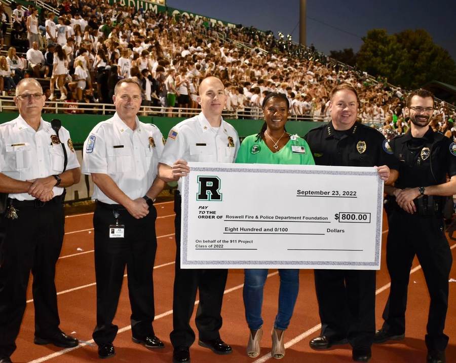 Roswell Fire and Police command staff accept a 911 Project donation at Roswell High School.