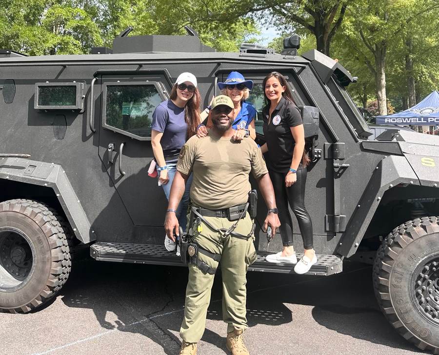 A Roswell Police tactical officer and residents beside a Roswell PD armored response vehicle.