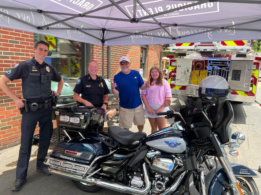Roswell Police officers and residents beside a Roswell PD Harley and Truck 24 downtown.