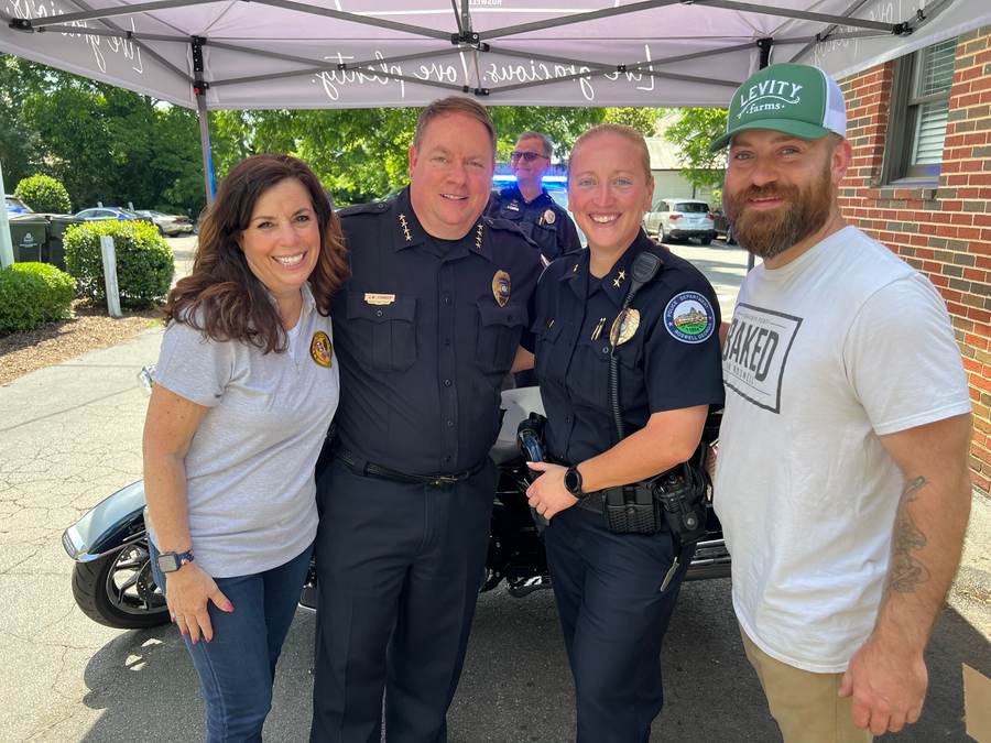 A Roswell Police chief and officers pose with neighbors at a community fundraiser.