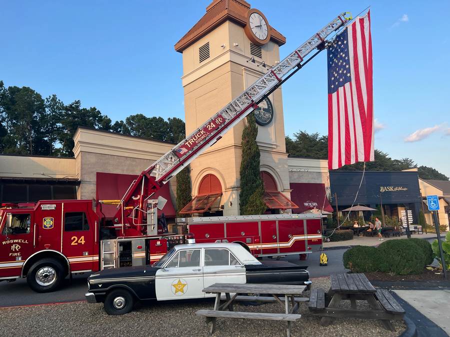 Roswell Fire Truck 24 raises a giant U.S. flag from its ladder by the historic clock tower.