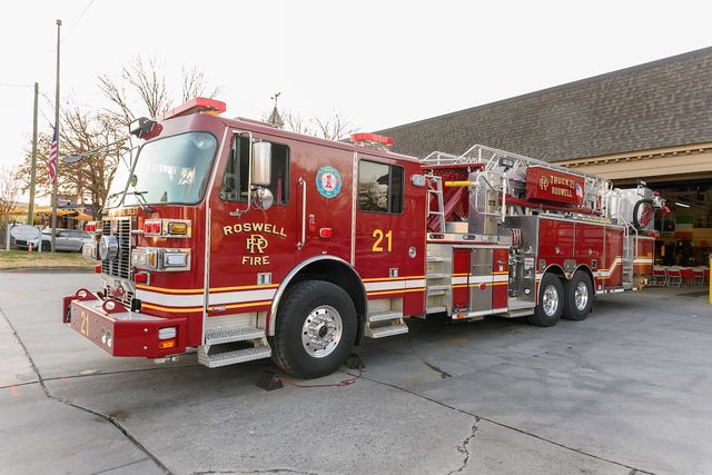 Roswell firefighters standing alongside a fire engine at the Ole Timers Dinner community event.